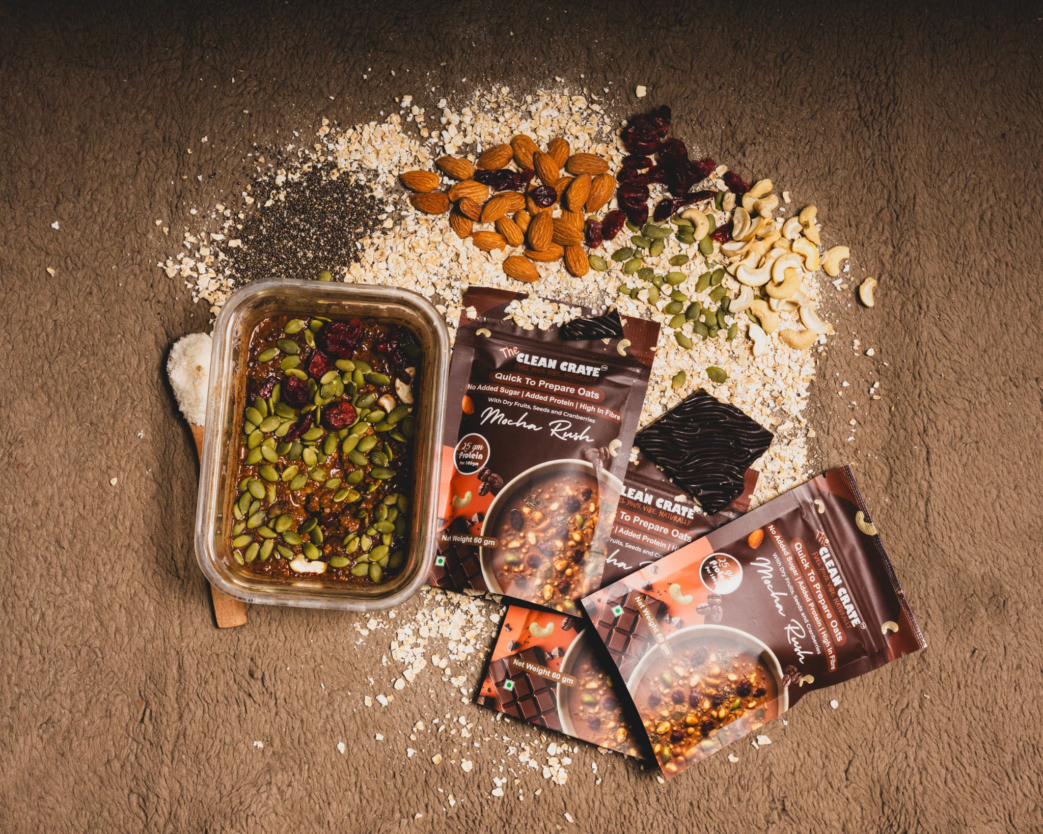 Mocha Rush packs beside loose oats, almonds, cashews and dark chocolate on a grey stone surface