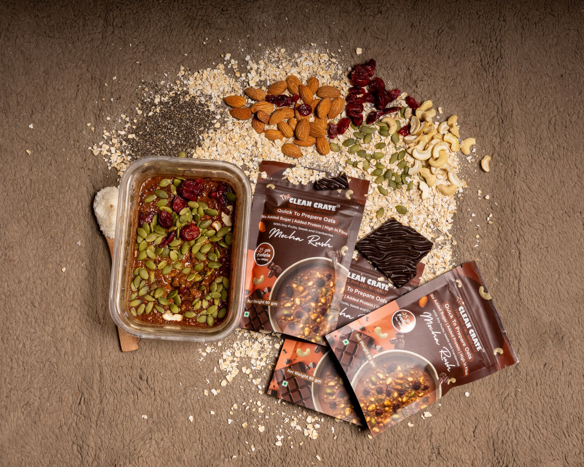 Mocha Rush packs on a grey stone surface beside a tub of prepared oats topped with pumpkin seeds and cranberries
