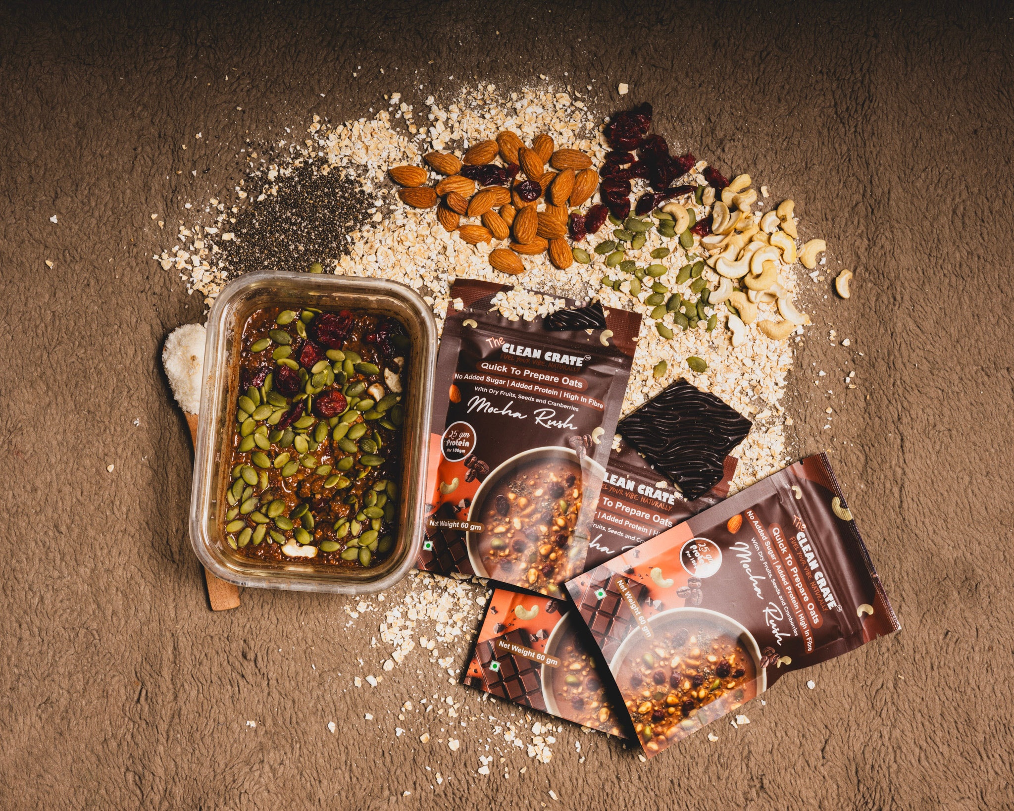 Mocha Rush packs beside loose oats, almonds, cashews and dark chocolate on a grey stone surface